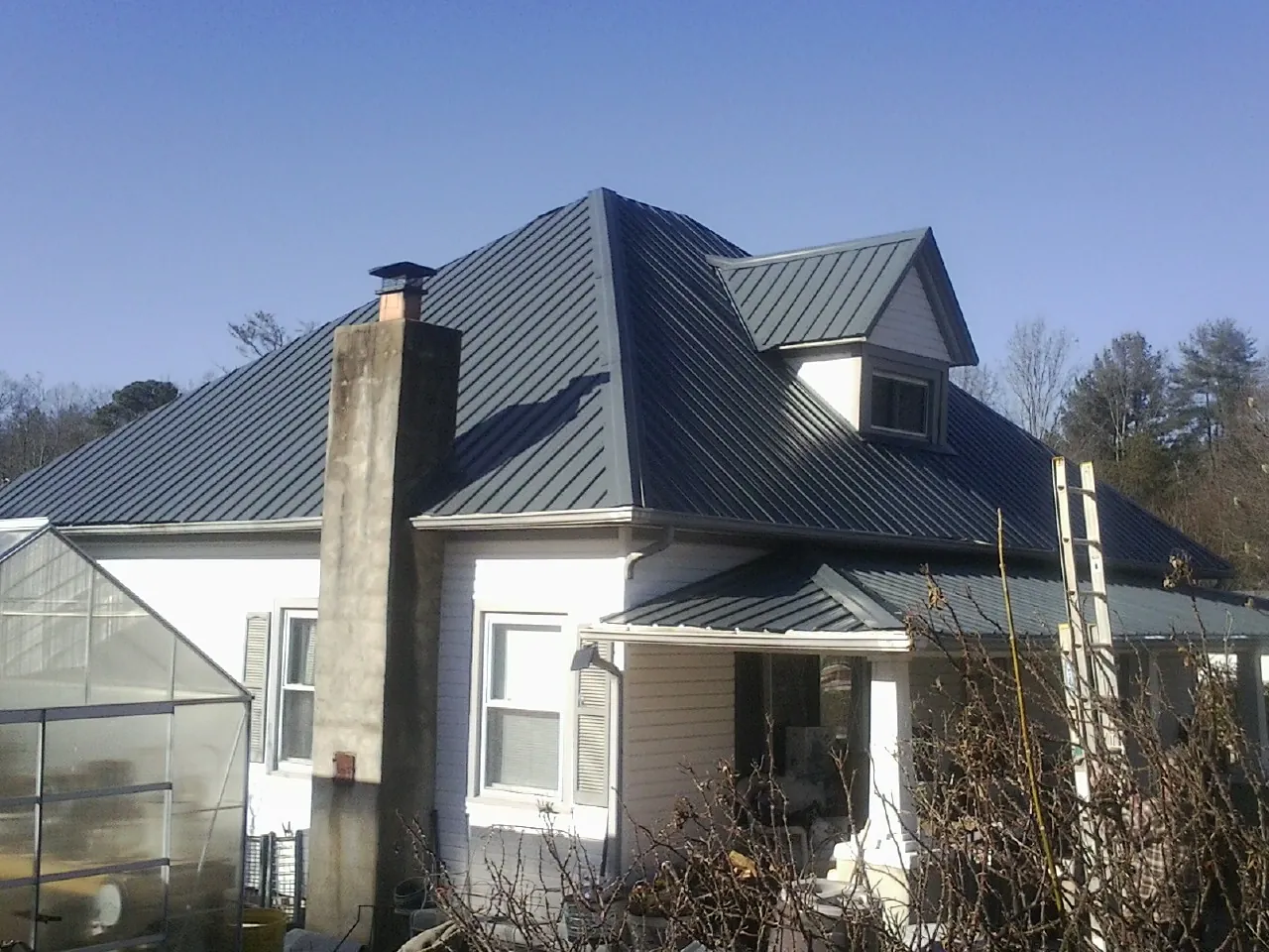 Dark blue standing seam metal roof on a white farmhouse with dormer — Slate & Tile Roof Repair by Roofing Brothers in Pescadero