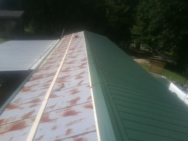 Old rusted panels beside newly installed green metal roofing — Wind Damage Roof Repair by Roofing Brothers in Pescadero