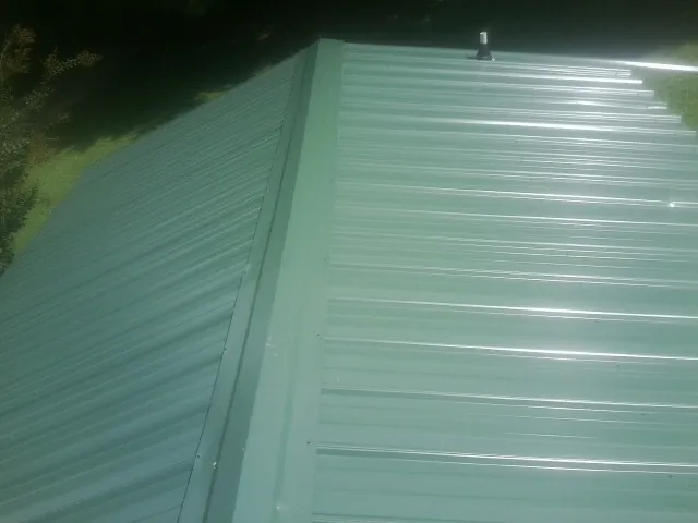New green metal panels meeting at the ridge of a roof — Flat Roof Repair work by our crew in Pescadero