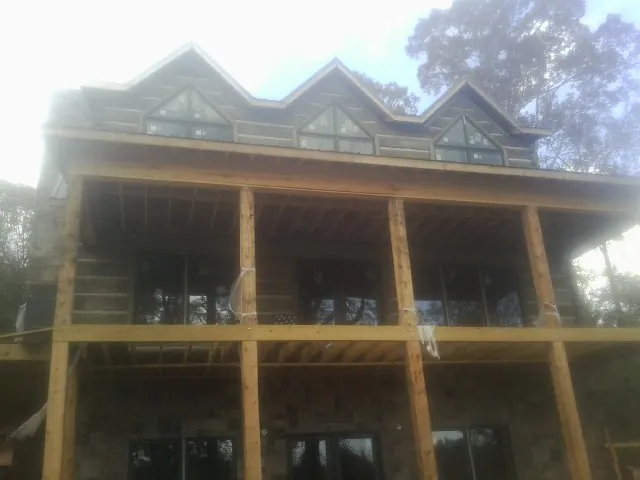 Dormers and porch framing on a large log home under construction — Roof Coating work by our crew in Pescadero