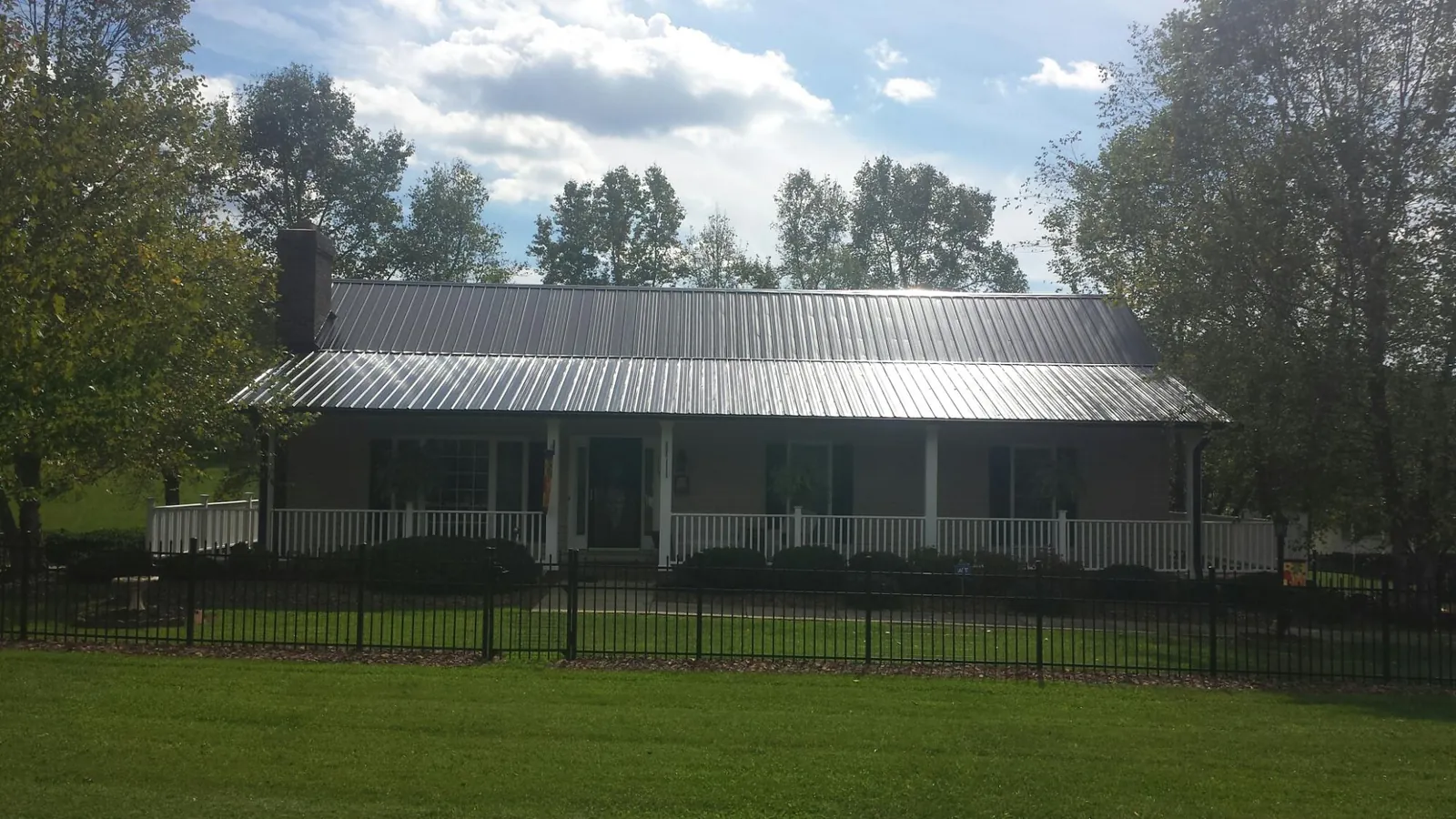 Gray metal roof on a brick ranch with a full width front porch — Gutter Guard Installation work by our crew in Pescadero