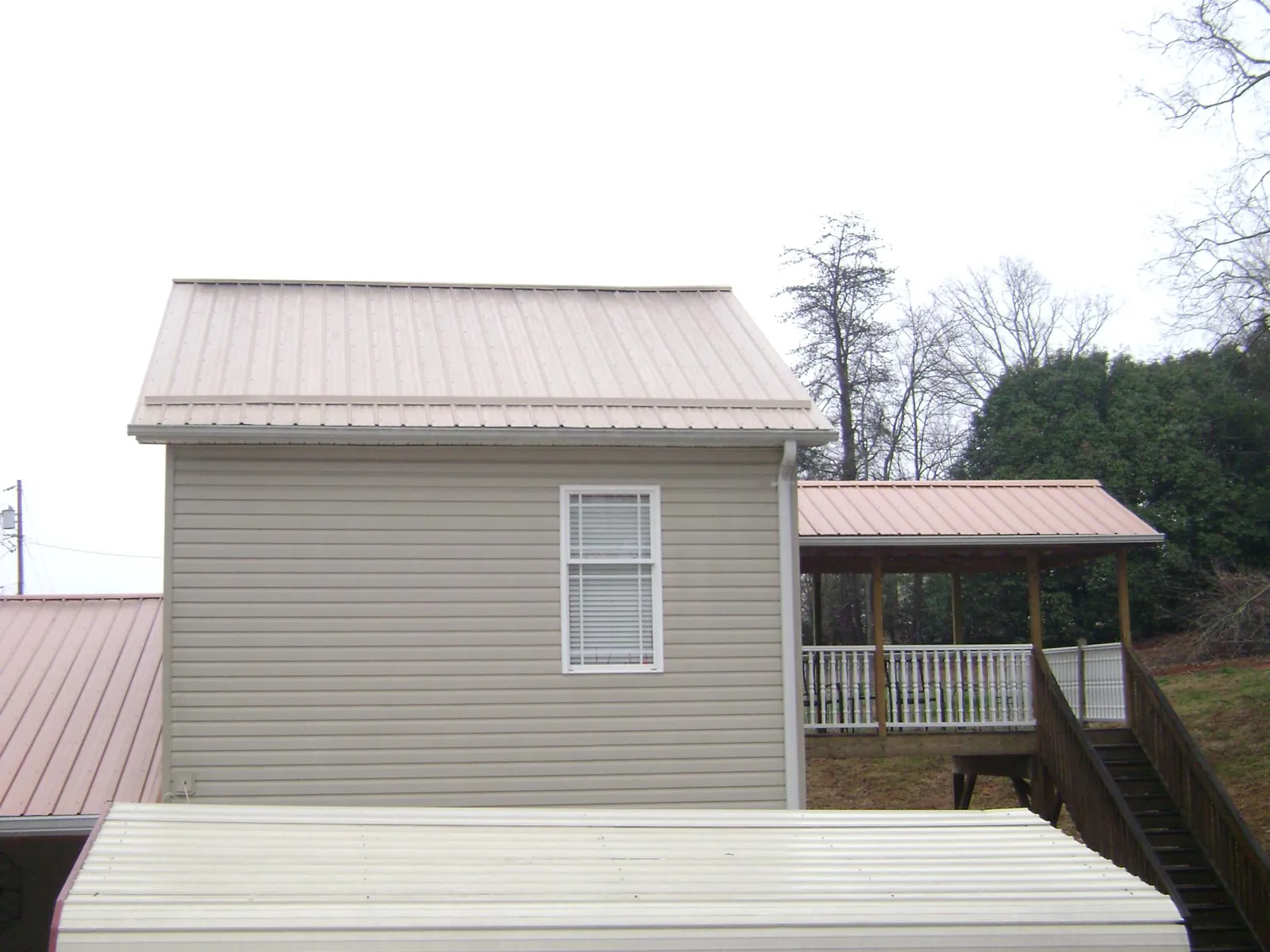 Tan metal roofs on a two story addition and attached porch, from a Roof Replacement job in Pescadero