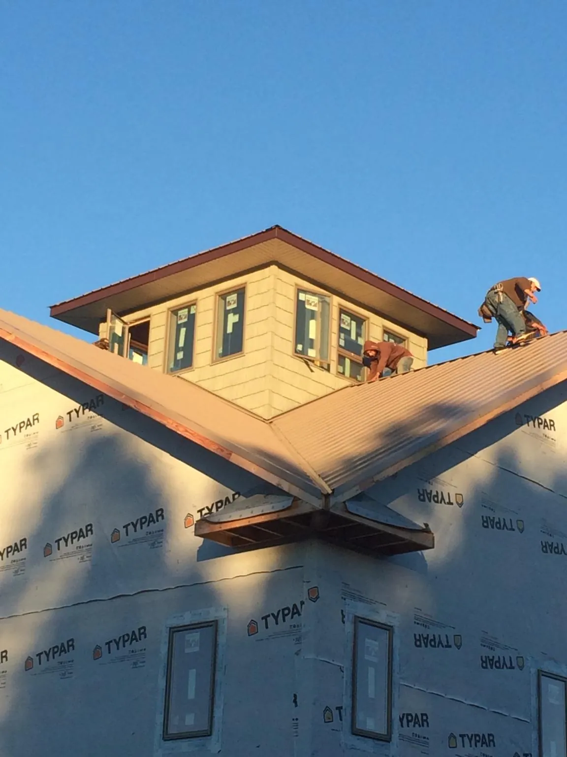 Roofers working around a rooftop cupola on a new metal roof at sunset — Roof Waterproofing in Pescadero by Roofing Brothers
